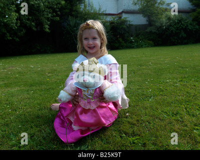 Fille habillée comme princesse avec un ours de princesse dedans A Garden Surrey Angleterre Banque D'Images