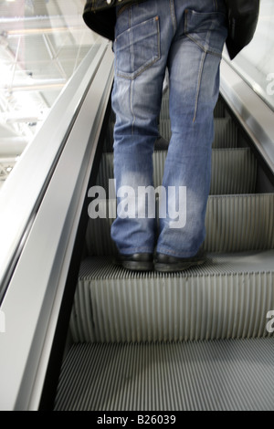 Personne en jeans debout sur déménagement escalator Banque D'Images