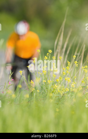 Cycliste avec arbustes en premier plan Banque D'Images