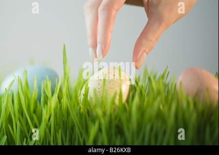 Woman Reaching for décoré d'oeufs dans l'herbe Banque D'Images