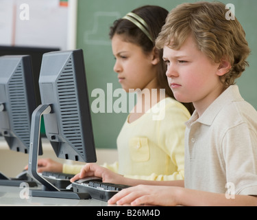 Les enfants de l'école multi-ethnique à la recherche à des ordinateurs Banque D'Images