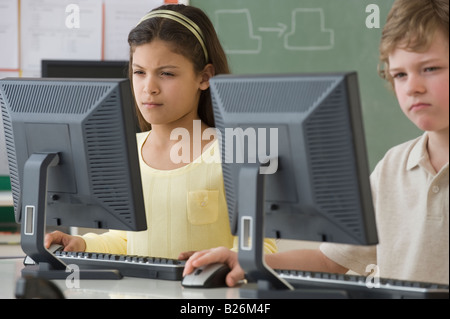 Les enfants de l'école multi-ethnique à la recherche à des ordinateurs Banque D'Images