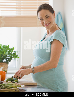 Pregnant Hispanic woman chopping vegetables Banque D'Images