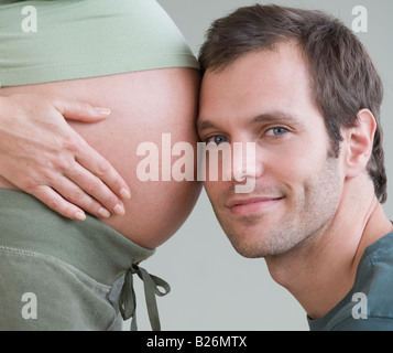 Hispanic man resting head sur le ventre de femme enceinte Banque D'Images