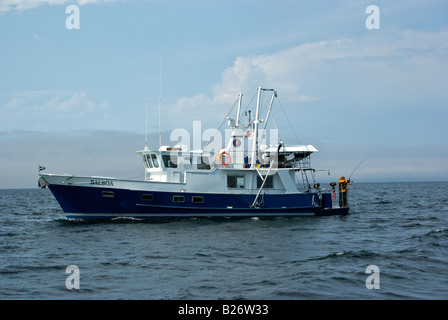 La lecture d'un pêcheur à bord d'un saumon luxury charter yacht de pêche à la traîne dans le Pacifique Nord Banque D'Images