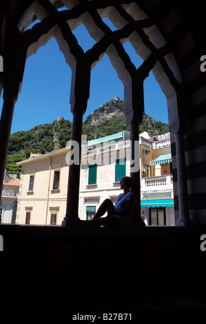 Une jeune fille assise à l'avant-toit de l'église dans une petite ville en Italie, donnant sur le perron de l'église ci-dessous Banque D'Images