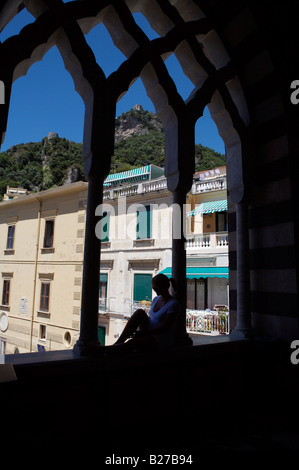 Une jeune fille assise à l'avant-toit de l'église dans une petite ville en Italie, donnant sur le perron de l'église ci-dessous Banque D'Images