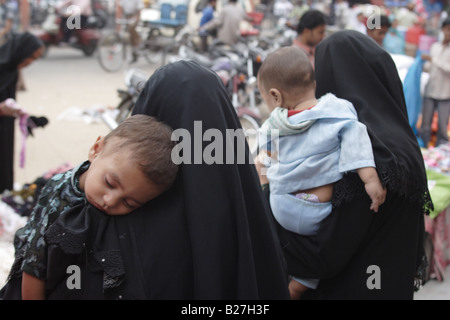 Deux femmes musulmanes en tchador avec leurs enfants à dormir dans une rue de Jaipur, Rajasthan, Inde. Banque D'Images