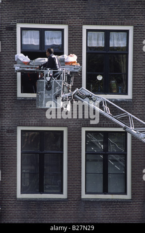 Homme malade d'être évacués par le service d'incendie en raison d'un escalier étroit dans l'ancien bâtiment. Amsterdam, Pays-Bas. Banque D'Images