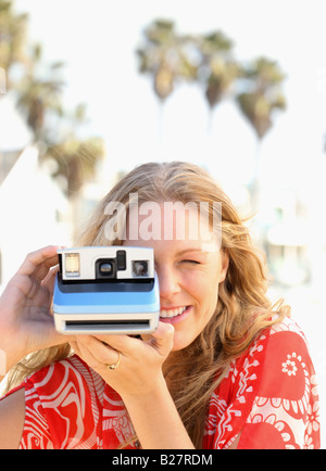 Woman taking photograph avec appareil photo instantané Banque D'Images