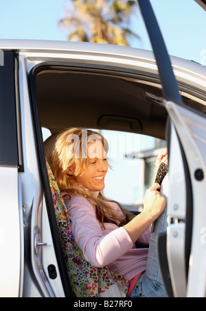 Femme assise en voiture avec porte ouverte Banque D'Images