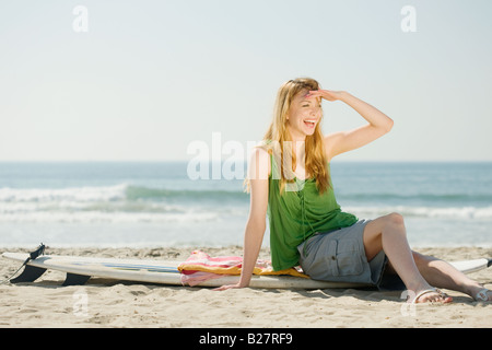 Femme assise sur une planche de surf Banque D'Images