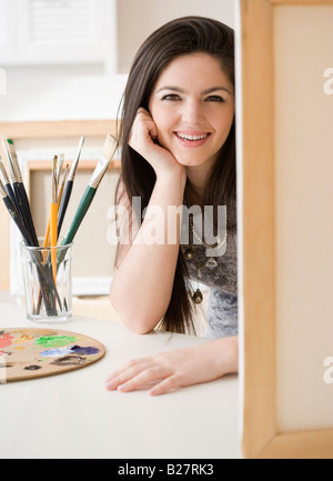 Femme à côté de pinceaux et toile Banque D'Images