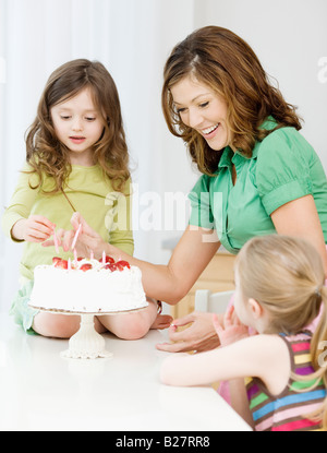La mère et les filles de décorer le gâteau d'anniversaire Banque D'Images