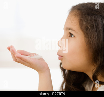 Young Girl blowing on feather in hand Banque D'Images