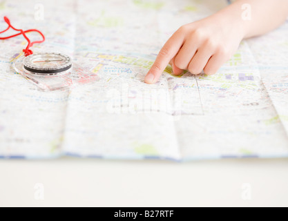 Enfant pointant sur la carte à côté de boussole Banque D'Images