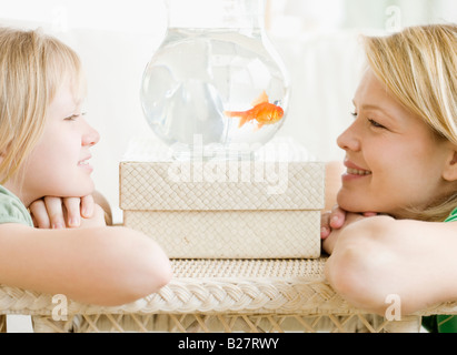 Mère et fille à la recherche de poisson dans bol Banque D'Images