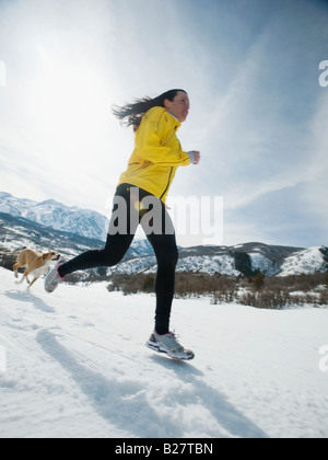 Femme et chien qui court dans la neige Banque D'Images