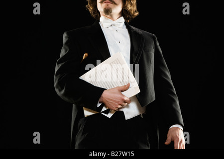 Man in tuxedo holding sheet music Banque D'Images