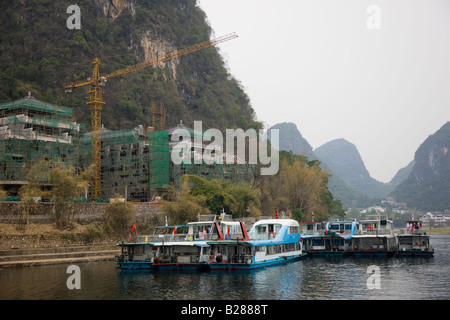 Bateaux de touristes amarré sur la rivière Li à Yangshuo par un site de construction de l'hôtel China Banque D'Images