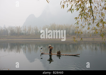 Pêcheur dans Suoyi manteau et coolie hat fishes avec cormorans sur Li River près de Guilin Chine Banque D'Images