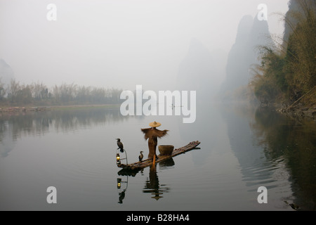 Pêcheur dans Suoyi manteau et coolie hat fishes avec cormorans sur Li River près de Guilin Chine Banque D'Images