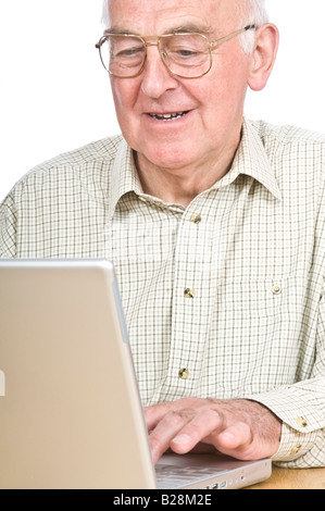 Un homme âgé à un bureau à l'ordinateur portable à un écran et souriant contre un blanc pur (255) Contexte. Banque D'Images