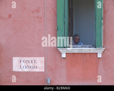 Femme âgée dans la fenêtre de la chambre sur l'île de Murano, Venise Banque D'Images