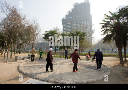 Les gens à pied dans un cercle dans le cadre de leurs exercices matinaux dans le parc par le mur de la ville de Xian Chine Banque D'Images