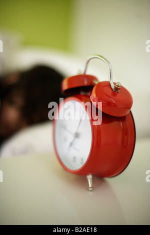 Fille de 5 ans dort dans son lit à côté d'un rouge vif réveil mixed race indian english Banque D'Images