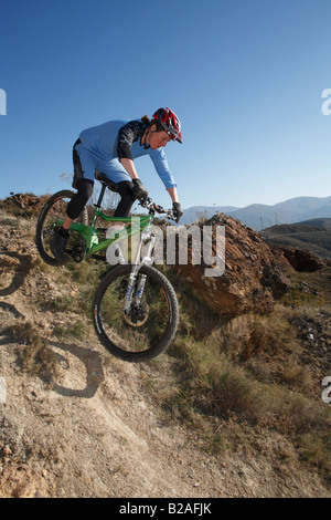 Vélo de montagne femelle passe au-dessus de roches dans la Sierra Nevada, Espagne Banque D'Images