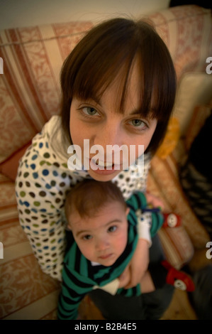 Vue grand angle drôle d'une jeune mère berçant son bébé tout en s'assit sur un canapé Banque D'Images