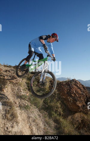 Vélo de montagne femelle passe au-dessus de roches dans la Sierra Nevada, Espagne Banque D'Images