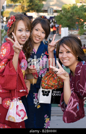 Trois professionnels des filles portant des robes yukata d'été le signe de la paix flash quand posant pour une photo Banque D'Images