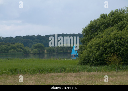 Voile bleu et les arbres - un bateau sur Hornsey simple, un vaste lac d'eau douce près de la mer à Hornsey dans l'East Yorkshire. Banque D'Images