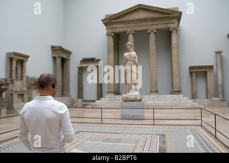 Un visiteur à la recherche de reliques de la Grèce antique et portant des écouteurs audio guide pour la visite de système Musée Pergamon de Museumsinsel Berlin Allemagne île Banque D'Images