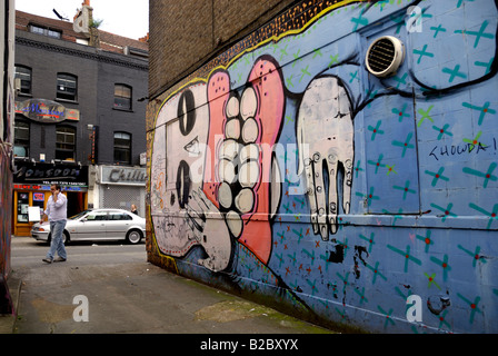 Homme marchant sur la rue par l'œuvre murale du 'Sweet Toof ('Burning Candy') London Banque D'Images