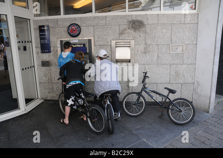 Les enfants se retirer de l'argent dans un distributeur automatique à Falmouth UK. Banque D'Images