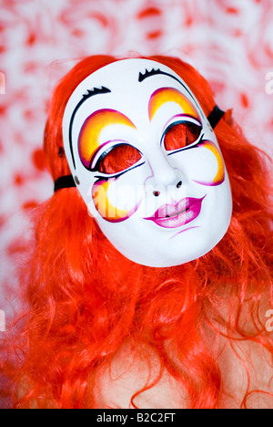 Portrai d'une femme avec une perruque rouge et masque de carnaval Banque D'Images