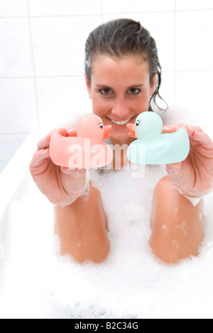 Jeune femme dans la baignoire à jouer avec les canards Banque D'Images