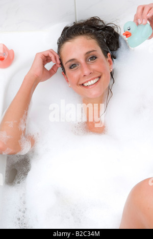 Jeune femme dans la baignoire à jouer avec les canards Banque D'Images