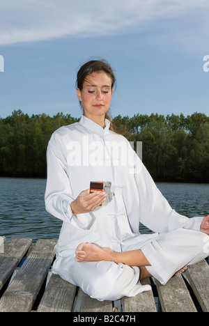 Woman practicing Yoga, demi-lotus pose, Ardha Padmasana, Mudra et phoning Banque D'Images