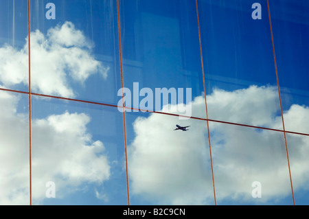 Ciel et nuages avion reflète dans la fenêtre d'un immeuble de bureaux modernes Banque D'Images