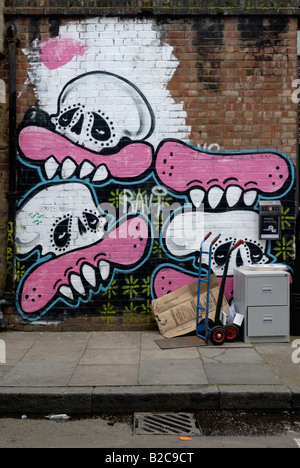 Gravure 'Candy' - 'Sweet Toof murale sur le mur de briques avec vintage cabinet et push cart en premier plan, Londres Banque D'Images