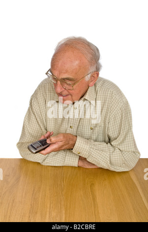 Portrait vertical d'un vieux monsieur ayant de la difficulté à voir et à utiliser les petits boutons sur un téléphone mobile. Banque D'Images