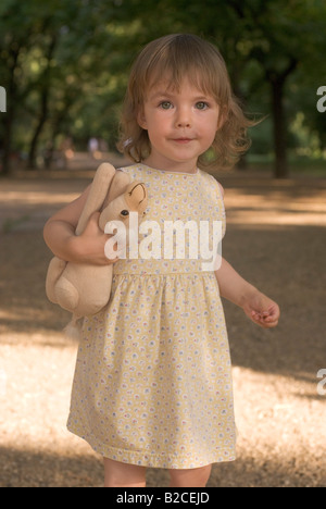 Petite fille dans parc avec peluche Banque D'Images