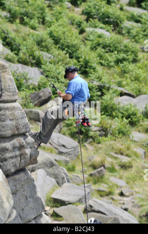 Rock climber abseiling sur Stanage Edge dans le Peak District Banque D'Images