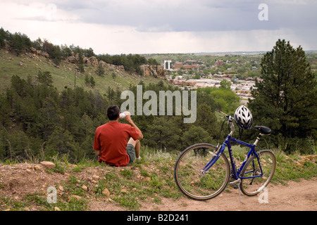 Cycliste sur M Hill (alias Cowboy Hill) avec le centre-ville de Rapid City dans la distance, Chuck Lien Family Park, Dakota du Sud Banque D'Images