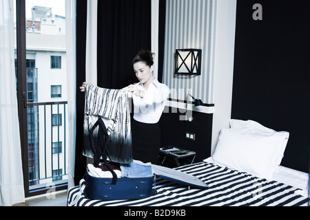 Belle femme valise d'emballage dans une chambre d'hôtel Banque D'Images