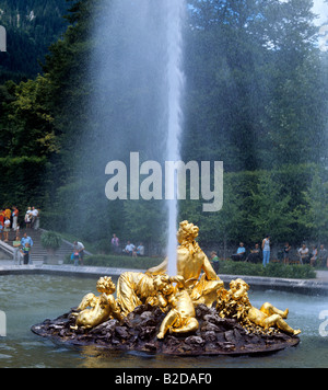 Fontaine dorée avec puissant jet d'eau dans le lac d'ornement par le château de Linderhof en Bavière et la flore chiffres Pattos Banque D'Images